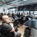 A diverse group of professionals attentively listening during an indoor business meeting in a modern conference room.
